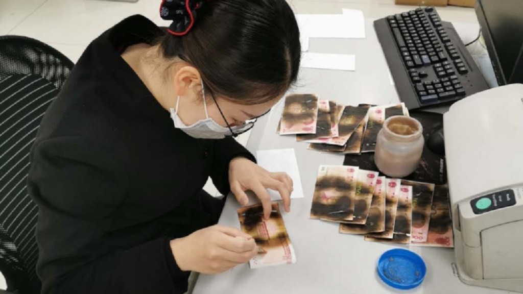 [Weibo photo of a bank teller inspecting the nuked money]